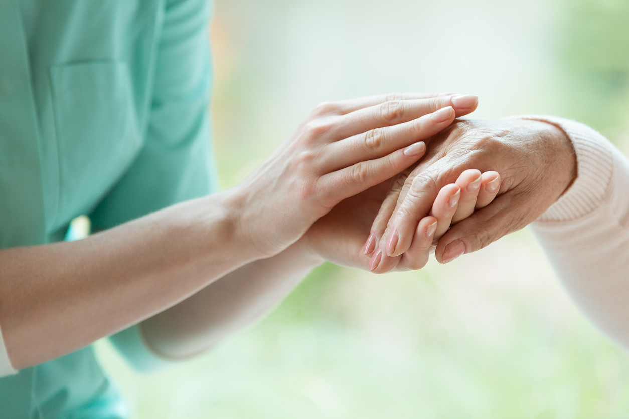 Caretaker massaging pensioner’s hand